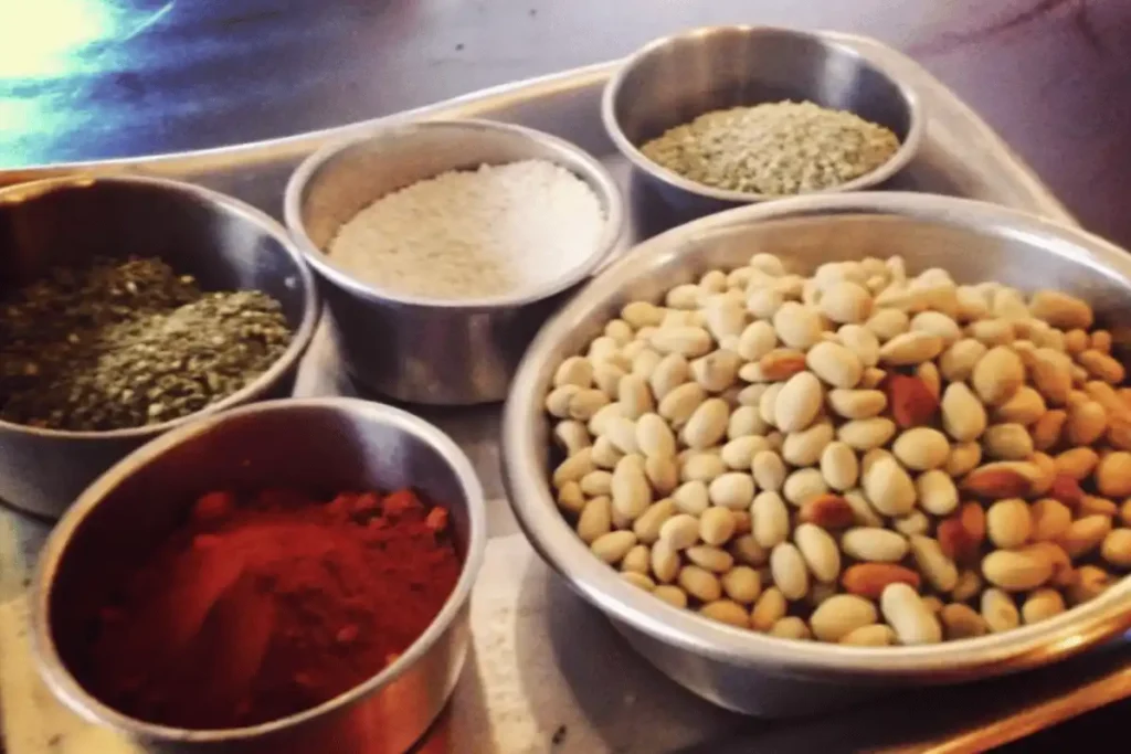 Dried and soaked Mayocoba beans in bowls with colorful ground spices on a tray